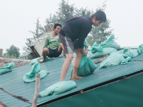 Một hộ dân ở Quảng Bình dùng bao cát để đè giữ mái nhà